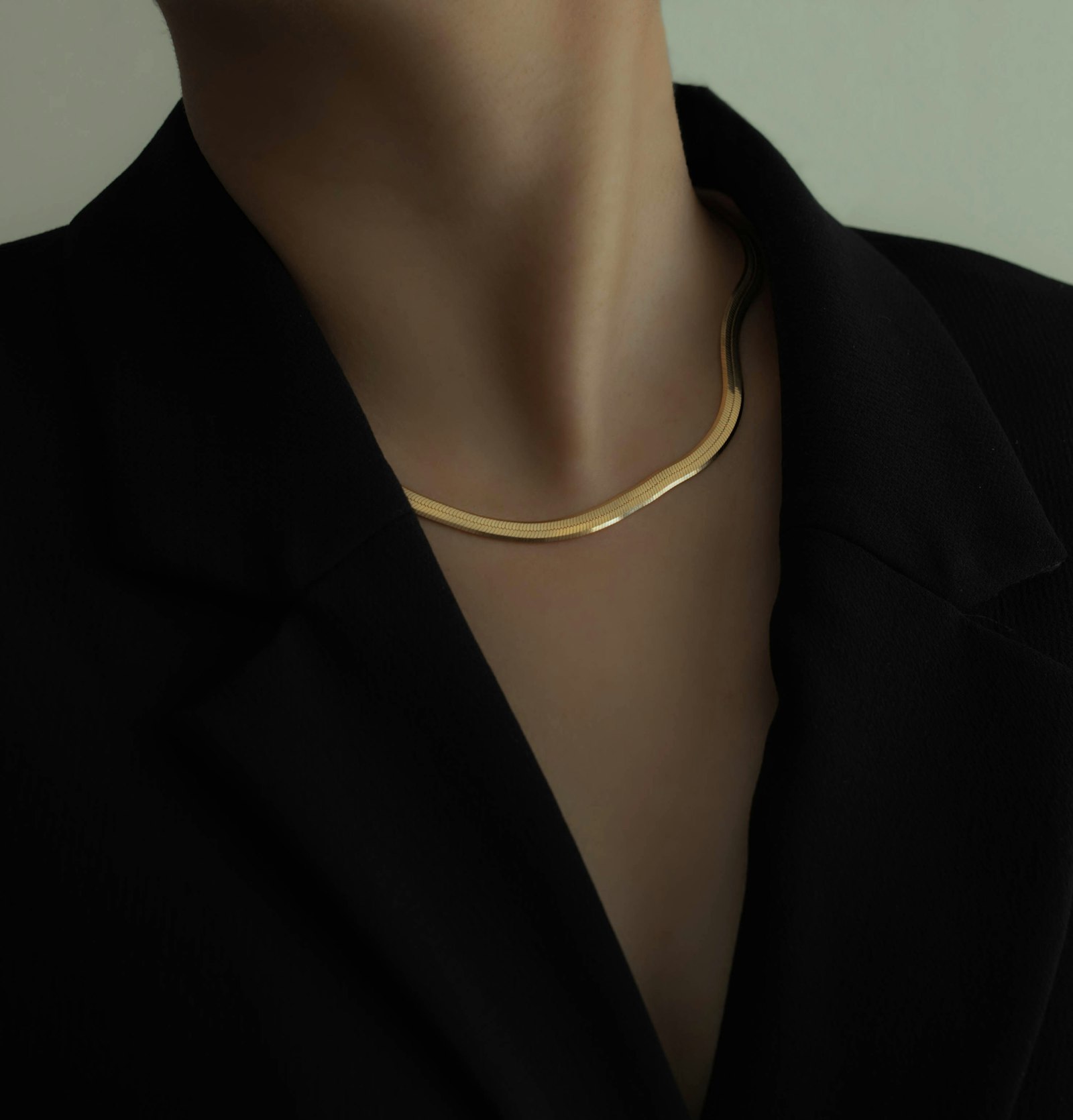 Woman in a black blazer wearing a layered gold necklace