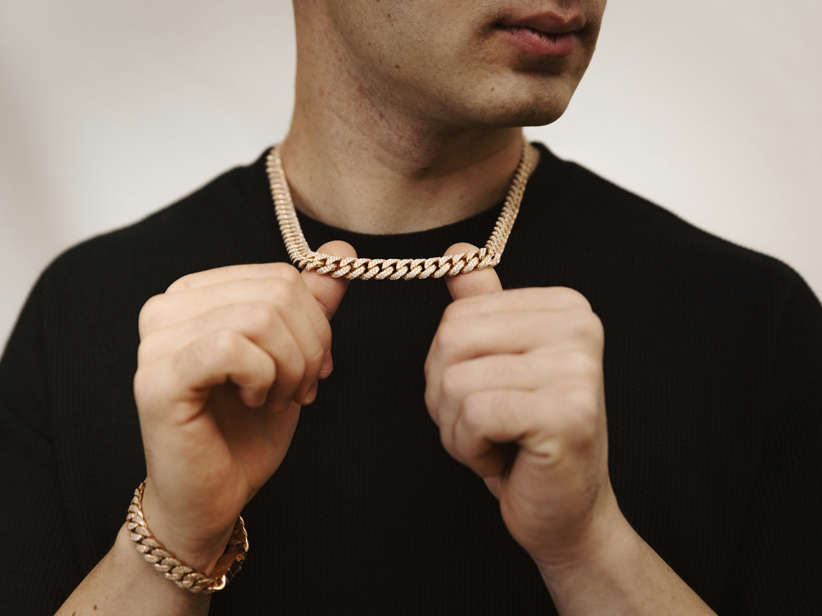 Man holding a gold chain necklace and bracelet